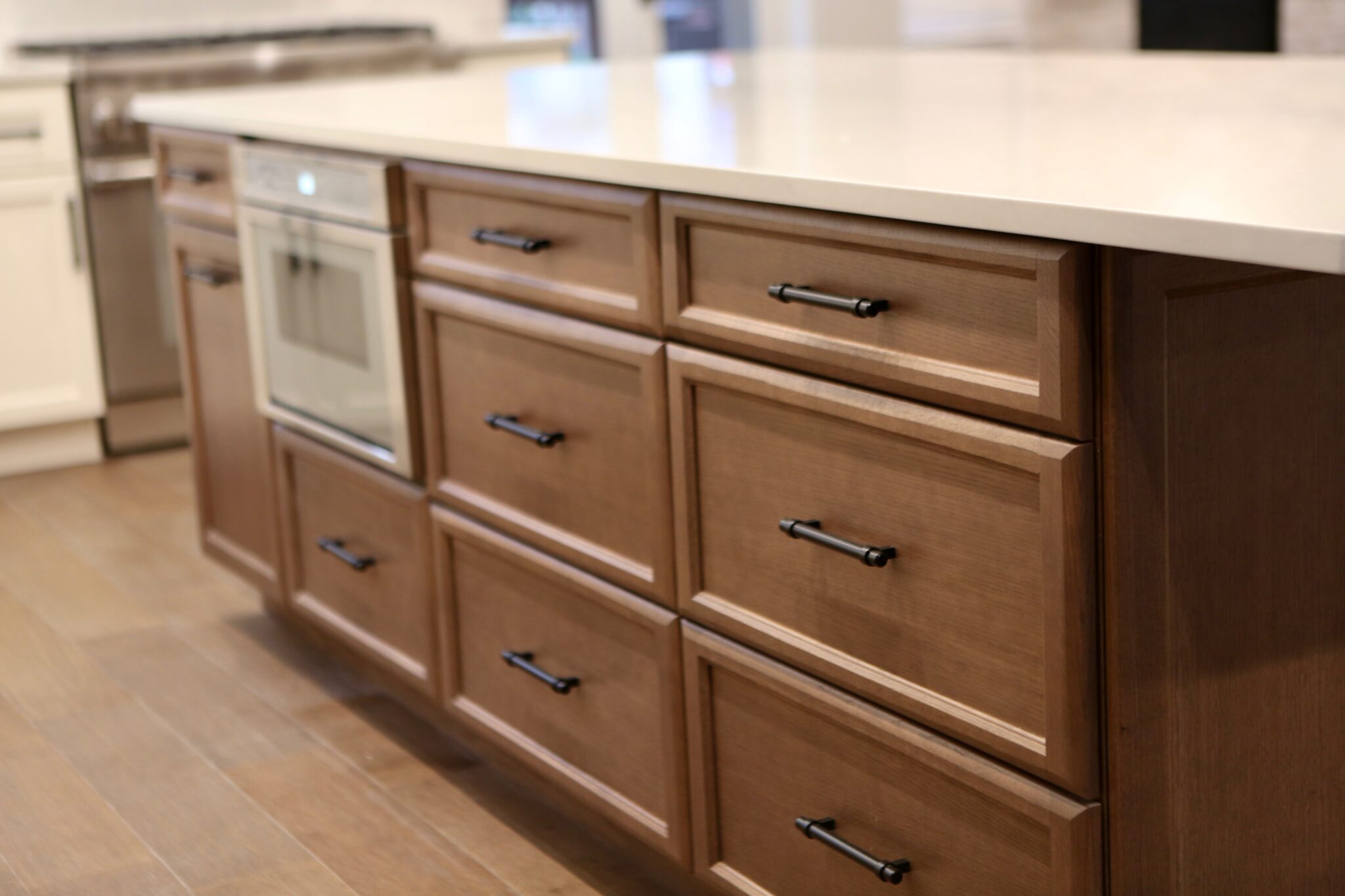 Close-up of a large kitchen island with wood drawers and built-in microwave